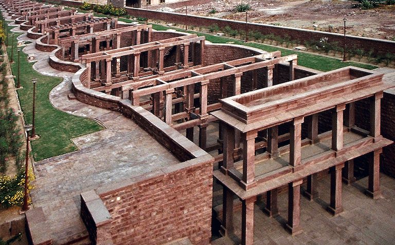 Birkha Bawari, a modern stepwell, built in 2009. Designed by Jodhpur based architect A. Mridul, it is a stepwell style water storage system in a housing township, Umaid Heritage, in the desert city of Jodhpur. Built to address severe water scarcity in the region, it has a capacity to collect 17.5 million litres of harvested runoff rain water from the site. ‘Birkha’ means ‘rain’ in the local dialect and ‘Bawari’ means a stepwell. Taking cues from ancient subterranean water buildings of the Indian sub-continent, the linear and the square step-wells, it has been designed as a combination of both the variants. Built of site-quarried red sandstone with a unique structural system of arcuated walls, it is an average of 12 meters wide, 227 meters long and 18 meters at its deepest end.